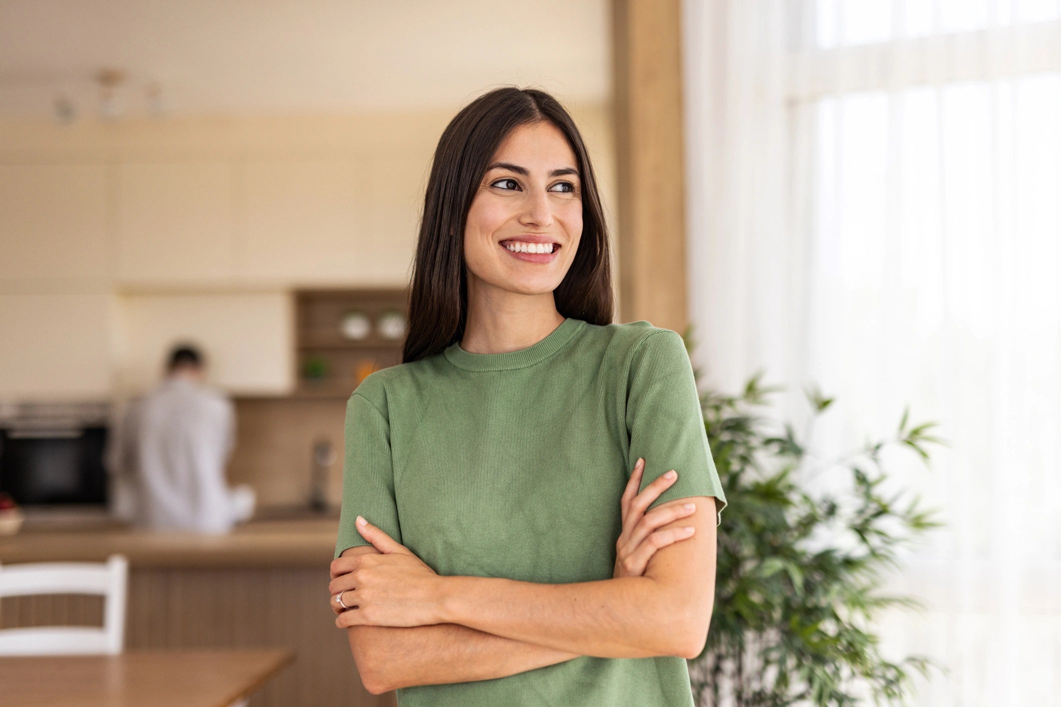 Cheerful woman smiling with folded arms in a modern kitchen